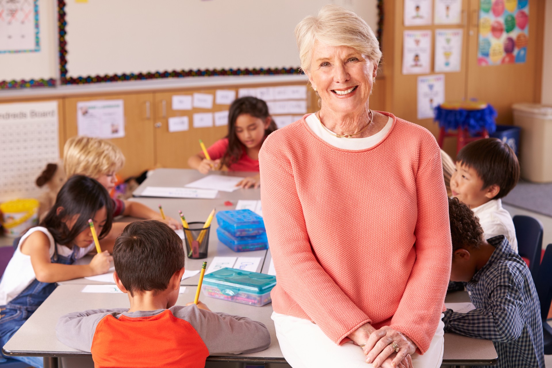 Senior teacher in classroom with elementary school kids